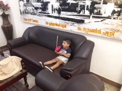 a little boy sitting in a leather chair at Arunaachalaa Inn in Palani