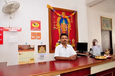 a man sitting at a desk in a room at Arunaachalaa Inn in Palani