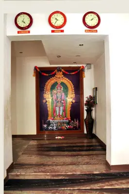 a room with a painting on the wall with two clocks at Arunaachalaa Inn in Palani