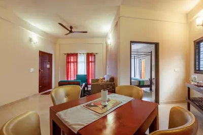 a dining room and living room with a table and chairs at Treebo Vrindavan, 3 Km From Madikeri Fort in Madikeri