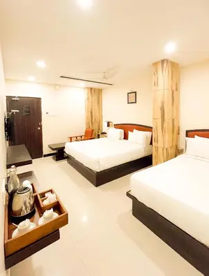 a hotel room with two beds and a desk at Shree Residency in Erode