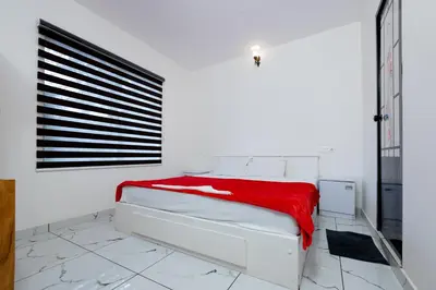 a white bedroom with a bed with a red blanket at Green Garden Jasmin Cottage in Vayittiri
