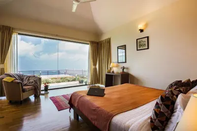 a bedroom with a bed and a large window at The Xanadu, Coonoor in Coonoor