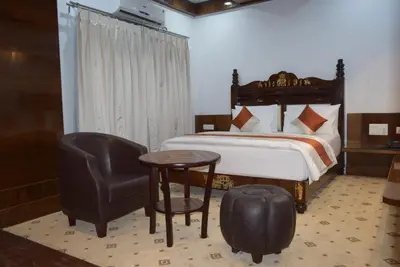 a bedroom with a bed and a chair and a table at Hotel Lok Sagar Mysore in Mysore