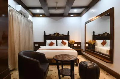 a bedroom with a bed and a mirror and a chair at Hotel Lok Sagar Mysore in Mysore