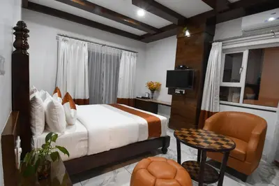 a bedroom with a bed and a tv and a chair at Hotel Lok Sagar Mysore in Mysore