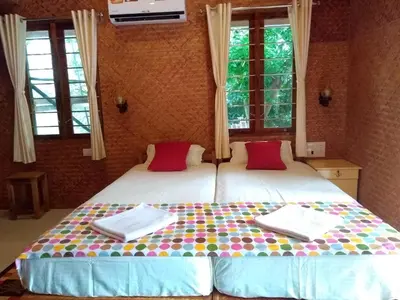 two beds in a room with two windows at Coconut Garden in Cherai Beach
