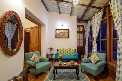a living room with two chairs and a table at SaffronStays Milton Abbott Estate - 2BR colonial-era bungalow with garden, golf course views & bonfire nights near Ooty Golf Club in Ooty