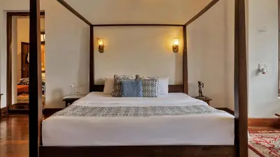 a bedroom with a four poster bed in a room at SaffronStays Milton Abbott Estate - 2BR colonial-era bungalow with garden, golf course views & bonfire nights near Ooty Golf Club in Ooty