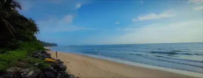 a beach with the ocean and a bunch of rocks at White Shell Beach House in Kannur