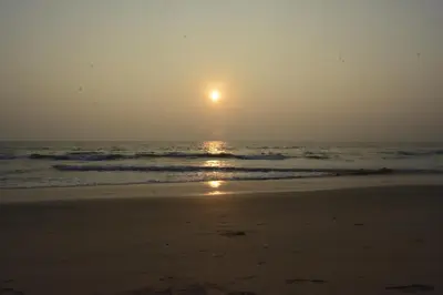 a sunset on a beach with the ocean at White Shell Beach House in Kannur