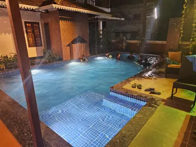 a group of people in a swimming pool at night at The Isle By Area 707 in Alwaye