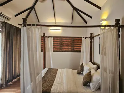 a bedroom with a canopy bed with white curtains at The Isle By Area 707 in Alwaye