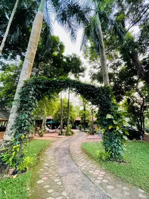 a path through a park with a arch covered in vines at The Isle By Area 707 in Alwaye