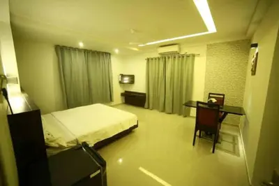 a bedroom with a bed and a desk and a table at Nalanda Inn in Palakkad