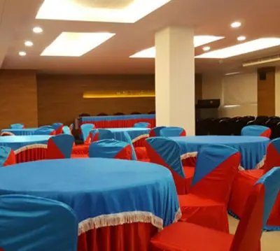 a room with blue and red chairs and tables at Nalanda Inn in Palakkad