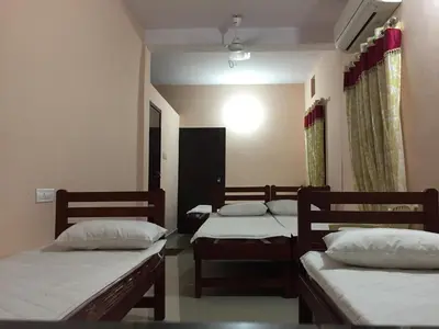 a room with three beds in a room at Mega Tourist Home in Guruvāyūr