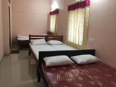 a room with three beds and two tables with pillows at Mega Tourist Home in Guruvāyūr