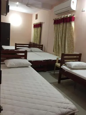 a room with two beds and two chairs in it at Mega Tourist Home in Guruvāyūr