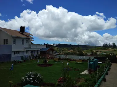 a house with a yard with benches in front of it at Drizzle Drop Inn in Ooty