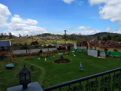 a yard with a playground with birds on the grass at Drizzle Drop Inn in Ooty