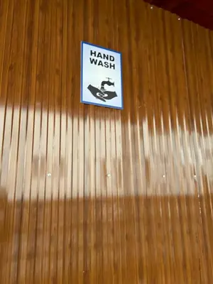 a sign on a wood wall with a hand wash sign at Hotel Jothi in Coimbatore