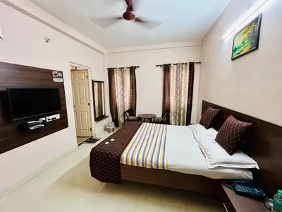 a hotel room with a bed and a flat screen tv at Hotel Jothi in Coimbatore