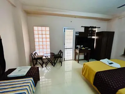 a room with two beds and a table and chairs at Hotel Jothi in Coimbatore