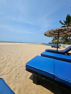 a group of blue lounge chairs and an umbrella on the beach at Veda5 Ayurveda Living Village in Trichūr