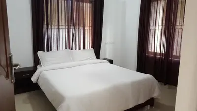 a white bed in a room with two windows at The Rubis in Kottakkal