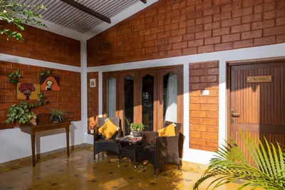 a patio with chairs and a table and a door at The Mangifera in Bandipūr