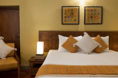 a bedroom with a bed with pillows and a lamp at The Mangifera in Bandipūr