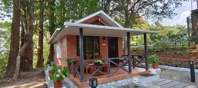 a small house with a porch in the woods at Monica Garden Bungalow in Vālpārai