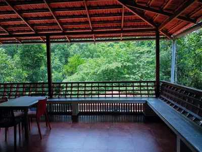 a screened in porch with a table and chairs at Heights Farm Stay - Coffee Estate Stay in Madikeri