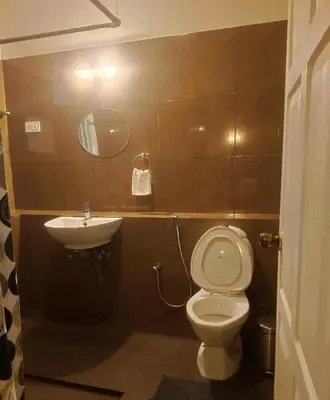a bathroom with a toilet and a sink at Puthuthottam Annexe in Vālpārai