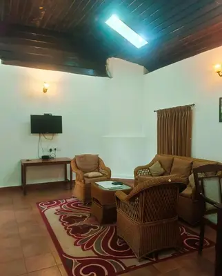 a living room with a couch and chairs and a tv at Puthuthottam Annexe in Vālpārai
