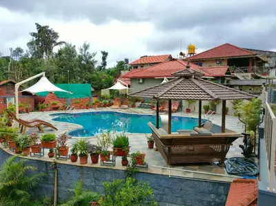 a resort with a swimming pool with a umbrella and chairs at Srinikethana Home Stay with Swimming Pool in Madikeri