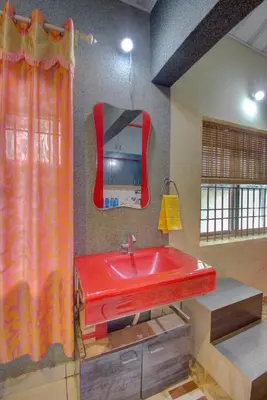 a bathroom with a red sink and a mirror at Srinikethana Home Stay with Swimming Pool in Madikeri