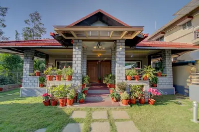 a house with potted plants on the front of it at Srinikethana Home Stay with Swimming Pool in Madikeri