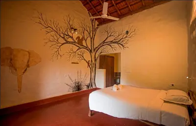 a bedroom with a tree painted on the wall at Deshadan Eco Valley Resort - An Eco friendly Mud House in Kanthalloor