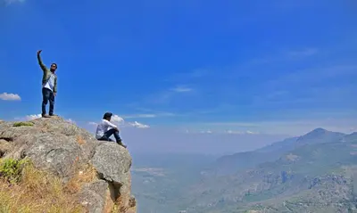 two people sitting on top of a mountain at Mist Resorts Ooty in Ooty