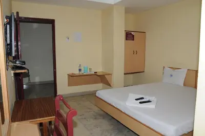 a bedroom with a bed and a table and a chair at Hotel Chanma International in Coimbatore