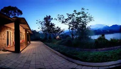 a building with a walkway next to a lake at Ottway Hills Mattupetty Dam in Munnar