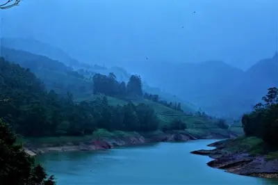 a river with trees on the side of a mountain at Ottway Hills Mattupetty Dam in Munnar
