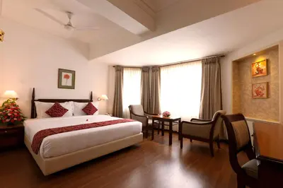 a hotel room with a bed and a table and chairs at Issacs Residency in Munnar