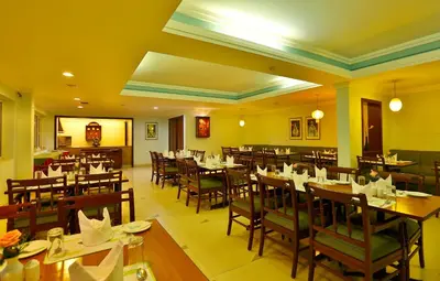 a restaurant with tables and chairs in a room at Issacs Residency in Munnar
