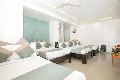 a room with four beds and a table with flowers at Aishwarya Le Royal in Mysore