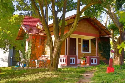 a small house with a tree in front of it at Chalets Resort Masinagudi in Ooty