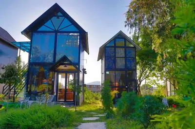 a blue house with glass windows in a garden at Chalets Resort Masinagudi in Ooty