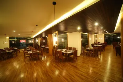 a restaurant with wooden floors and tables and chairs at Woodies Bleisure Hotel in Kozhikode